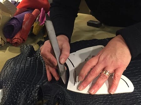 Taglio a mano di una pelle di coccodrillo nera lungo il bordo della sagoma