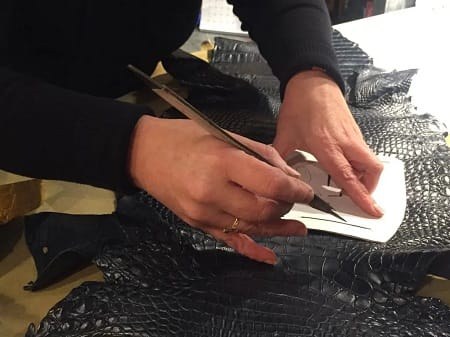 Tracciatura del modello sulla pelle di coccodrillo, con il cartamodello tenuto fermo