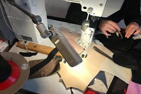 Cucitura della tomaia alla macchina a colonna, sotto la lampada del banco